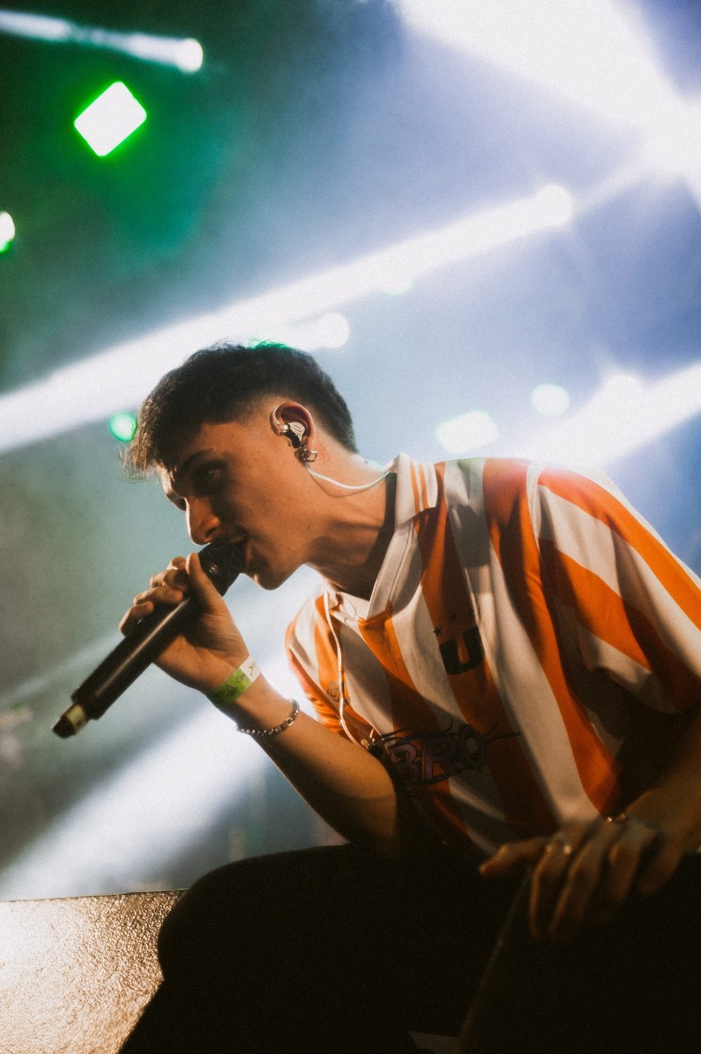 Lucas Gavvi singing on stage under green and blue lights